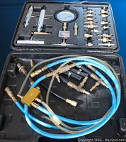 Bottom section of the case with several blue and clear hoses and brass connectors loose inside.