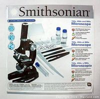Photo of the Smithsonian Microscope Kit box displaying the microscope with magnifications 150x, 450x, 900x, plus illustrations of included accessories and kit features.