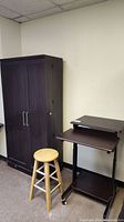 Office storage cabinet, wooden stool, and projector stand arranged against wall