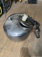 Full view of the antique cow milking machine showing the metal container, handle, and attached tubing with milking claw.