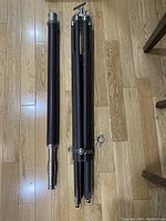 Image showing the collapsed wooden tripod stand and the telescope tube side by side on wooden floor.