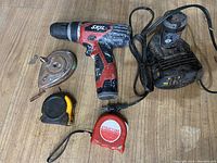 Photo of Skil cordless drill, charger, and measuring tapes on wooden surface with good lighting.