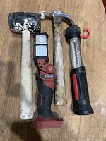 Photo showing two hammers and two work lights on wooden surface.