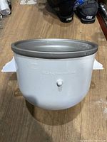 Front view of KitchenAid ice cream maker bowl showing shape, branding, and mounting tabs.