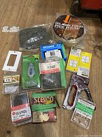 Photo showing misc hardware items including staple gun, chain, boxes of staples, glass etch pipe wrap, electrical outlet cover, sanding sponge.