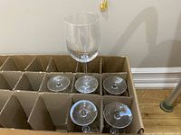 One wine glass standing upright inside a cardboard box with individual compartments, showing the full shape including stem and bowl.