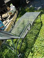 Full view of the metal chaise lounger placed on grass outdoors, showing the metal mesh surface and adjustable backrest.