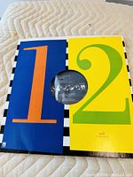 Colorful sleeve showing large numerals '1' and '2' with the vinyl partially visible in the center opening.