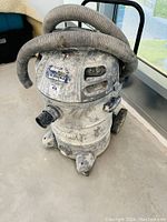 Front and side view of the Shop Vac contractor wet/dry vacuum showing attached hose and condition of body and wheels.