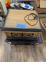 Top view of Bell Howell record player closed showing wood-grain finish top with black trim and power cord