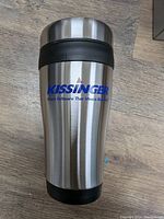 Front view of a stainless steel insulated travel mug with black grip and KISSINGER branding.