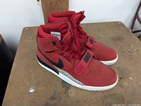 Side view of red Jordan Legacy 312 sneaker showing black Nike Swoosh, red laces, and textured midsole with elephant print detail.