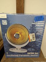 Box front of an oscillating parabolic heater showing model, wattage, and safety features.