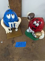 Front view of red and blue M&M candy dispensers on a wooden surface