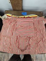Red and white vertically striped apron displayed folded with front pocket visible