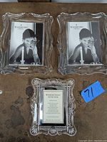 Three Waterford crystal picture frames arranged on a surface: two larger frames with wavy edges and a smaller frame with leaf pattern edges.