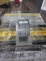 Top view showing rectangular glass surface of the coffee table with rounded edges and curved metal base beneath.