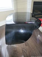 Black modern molded acrylic coffee table with glossy finish, curved wave-like shape, visible surface scratches and scuffs.