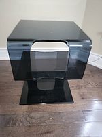 Front view of the black tinted molded acrylic S-shaped side table showing its curved modern design and smooth finish.
