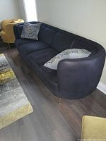 Front-right angle view of sofa showing curved side and metal legs, includes two pillows