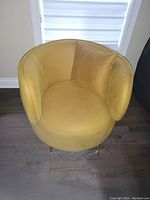 Front view of the yellow upholstered tub chair with matching cushion on hardwood floor.