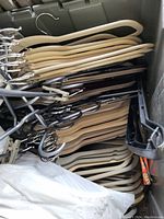 Top view of bin showing neatly stacked light wood and metal coat hangers with clips.