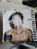 Photo of the Wiz Khalifa Blacc Hollywood vinyl record cover showing artist with tattooed chest blowing smoke, album title visible
