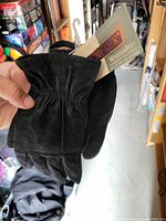 Black suede gloves being held with tags visible showing Wonder brand and WonderFit collection.