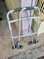 Foldable walker with two front wheels and rubber tips on the back legs. Padded hand grips and adjustable height.