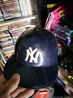 Front and side view of navy blue New York Yankees batting helmet with white NY logo.
