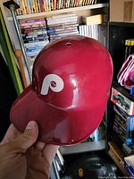 Side view of curved white 'P' logo on glossy red helmet shell.