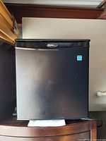 Front view of black Danby mini bar fridge showing door and logo.
