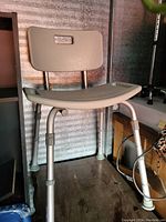 Front angled view of the adjustable aluminum shower chair with beige seat and backrest, showing height adjustable legs and rubber tips.
