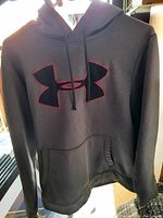 Gray Under Armour pullover hoodie sweater with large black and red logo on chest.