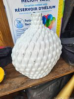 White decorative ceramic vase with textured bubble pattern on a wooden surface.