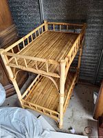 Front angle view of the two-tier bamboo wooden stand showing slatted shelves with railing and curved supports under top shelf.