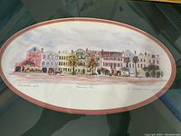 Frontal view of the framed watercolor depicting pastel Rainbow Row houses in Charleston, SC with artist signature and matting.
