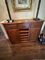 Front view of the antique wooden buffet cabinet showing the closed drawers, cupboards, and wine rack