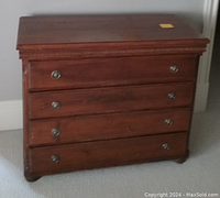 Front view of antique wooden dresser with three drawers, metal ring pull handles, decorative molding along top edge, in a brown finish.