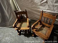 Pair of antique wooden kids rocking chairs showing front and side views in a dimly lit room.