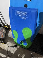 Photo of the underside of blue foam boogie board showing green fin-shaped accents and attached black coiled leg rope for foot.