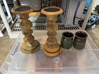 Photo of two wooden candle holders and two green ceramic mini vases on a plastic storage container.