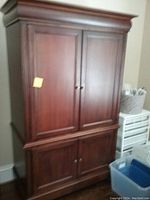 Front view of large cherry wood armoire with closed double doors showing its overall condition