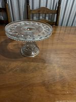 Side view of clear crystal cake stand showcasing pedestal base and decorative rim