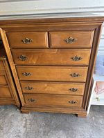 Front view of wooden chest of drawers dresser with six drawers and ornate brass handles.