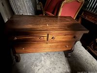 Front view of a wooden dresser with two drawers, wooden decorative knobs, and a flat top surface.