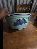 Side view showing green bowl with hand-painted blue grapes and green leaves on exterior