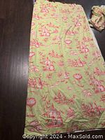 Full view of green curtain with pink oriental landscape print spread on floor