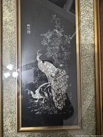 Full view of the framed peacock artwork featuring two peacocks, floral elements, and Chinese characters on black background.
