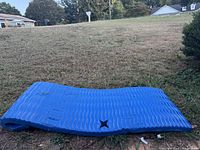Blue pool raft laid out on grass, showing wave pattern and star-shaped holes